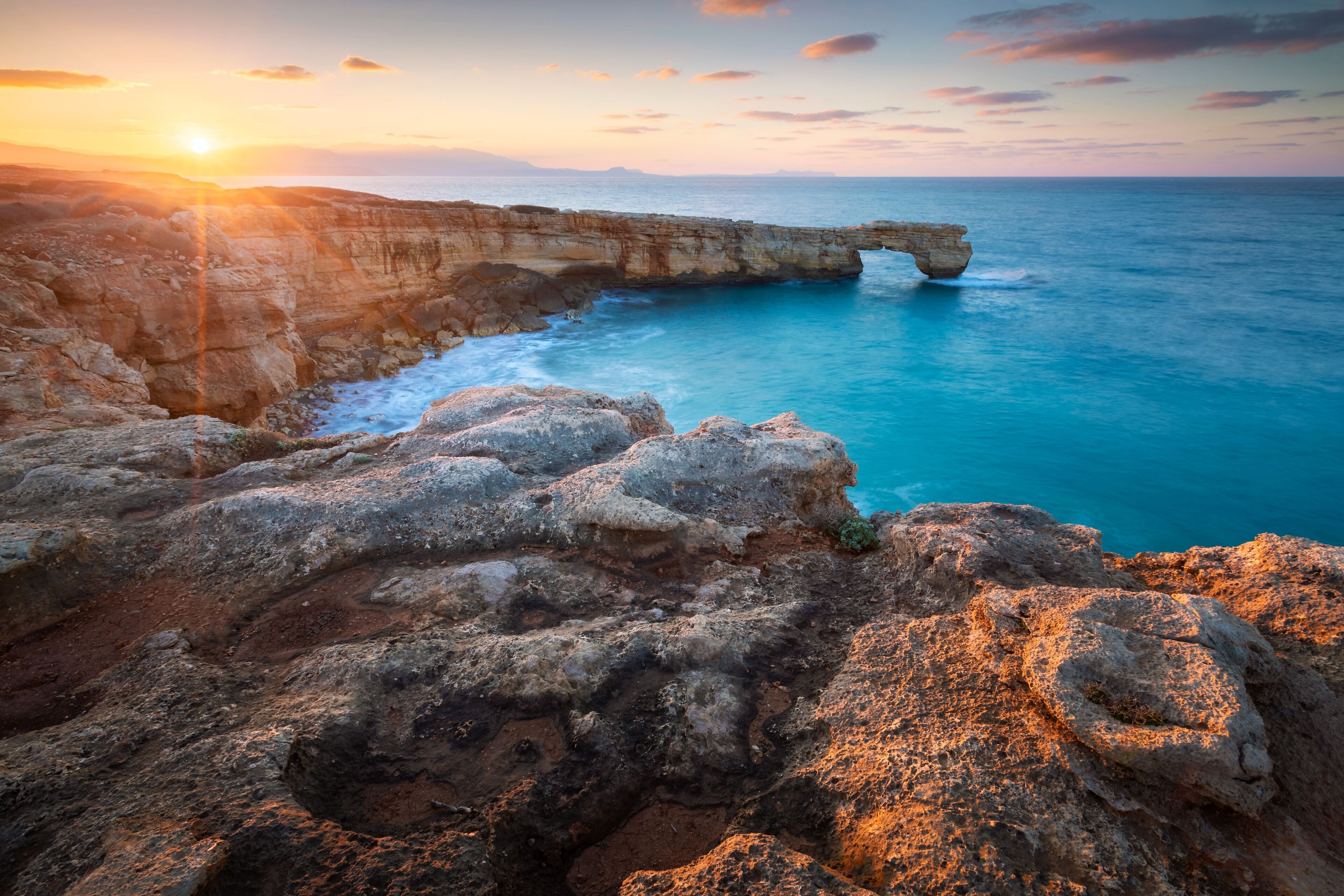 A coastal landscape with a prominent rock formation and a sea arch.
