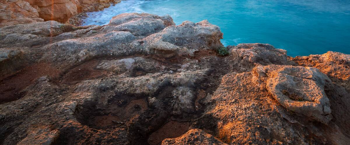 A coastal landscape with a prominent rock formation and a sea arch.