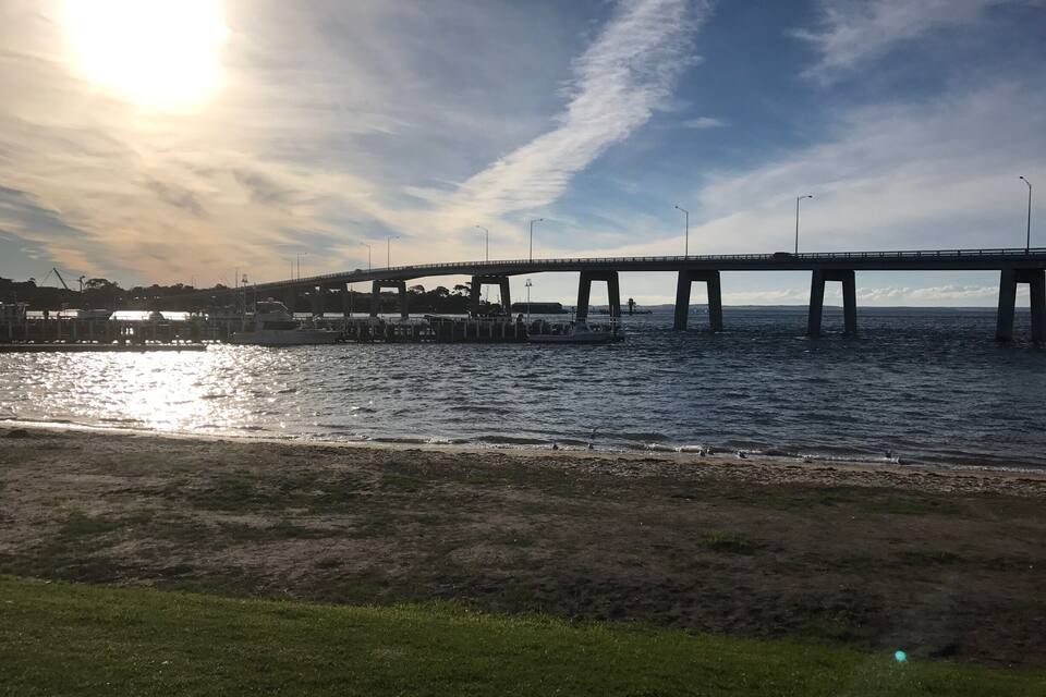 A bridge over water with a clear sky and sunlight reflecting on the surface.