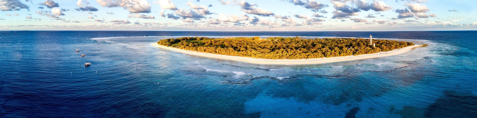 Vista aérea de uma pequena ilha com vegetação densa e um farol.