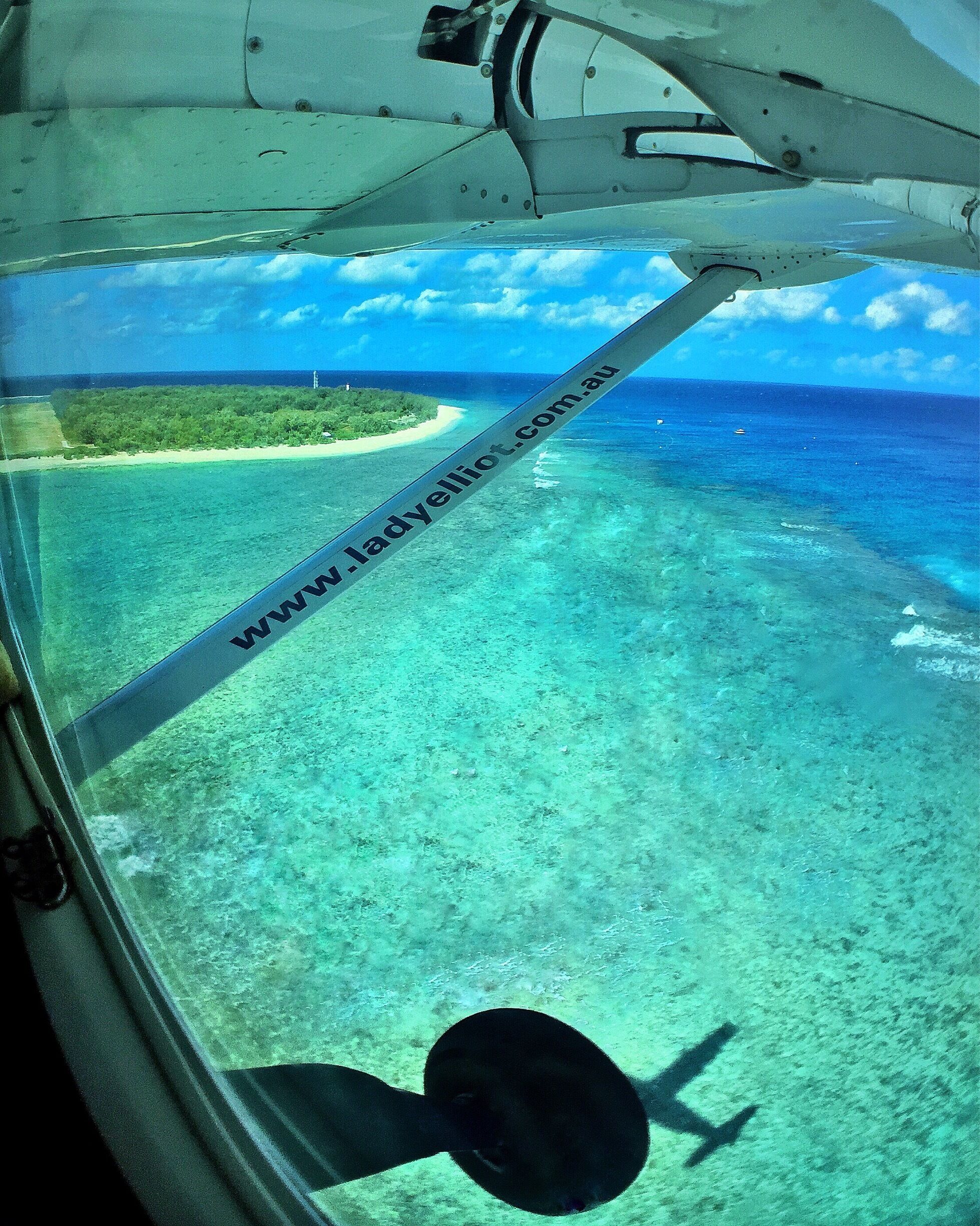 A clear view of a tropical beach with turquoise waters and a sandy shore.
