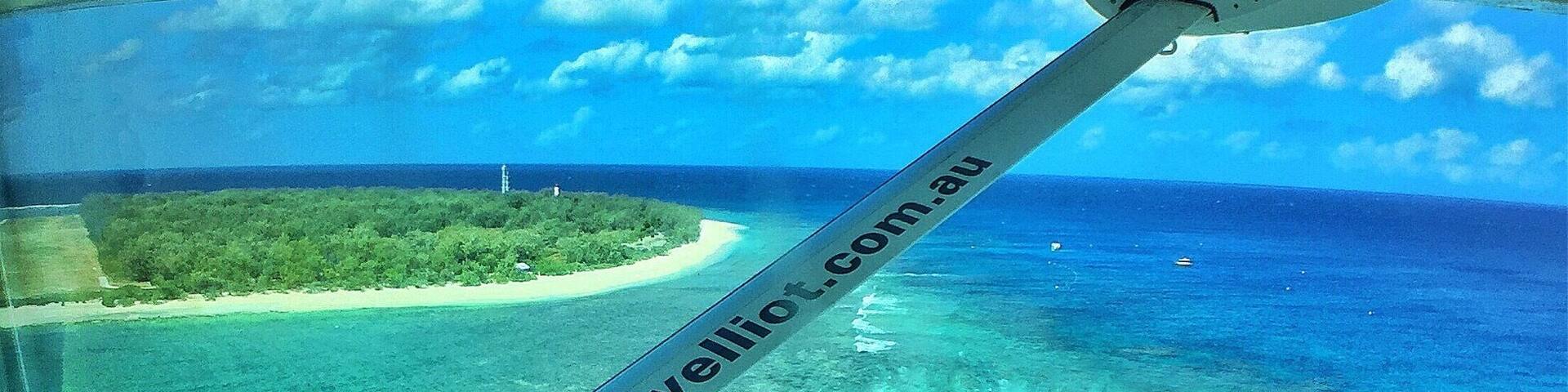 A clear view of a tropical beach with turquoise waters and a sandy shore.