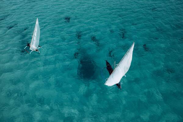 Two sailboats on turquoise water.