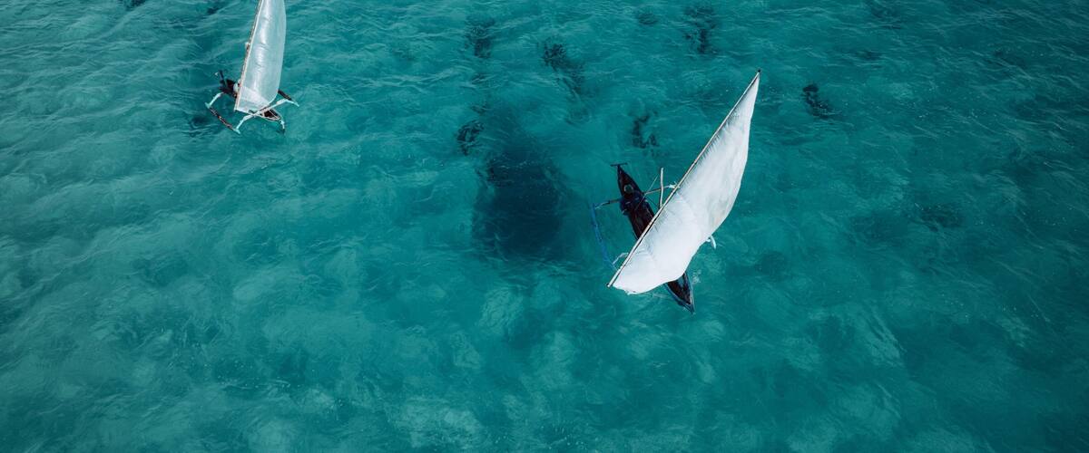 Two sailboats on turquoise water.