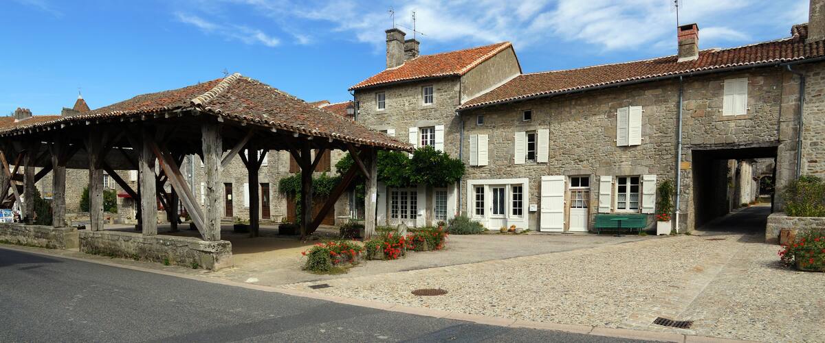 A stone building with a tiled roof, a wooden pavilion, and a cobblestone courtyard.