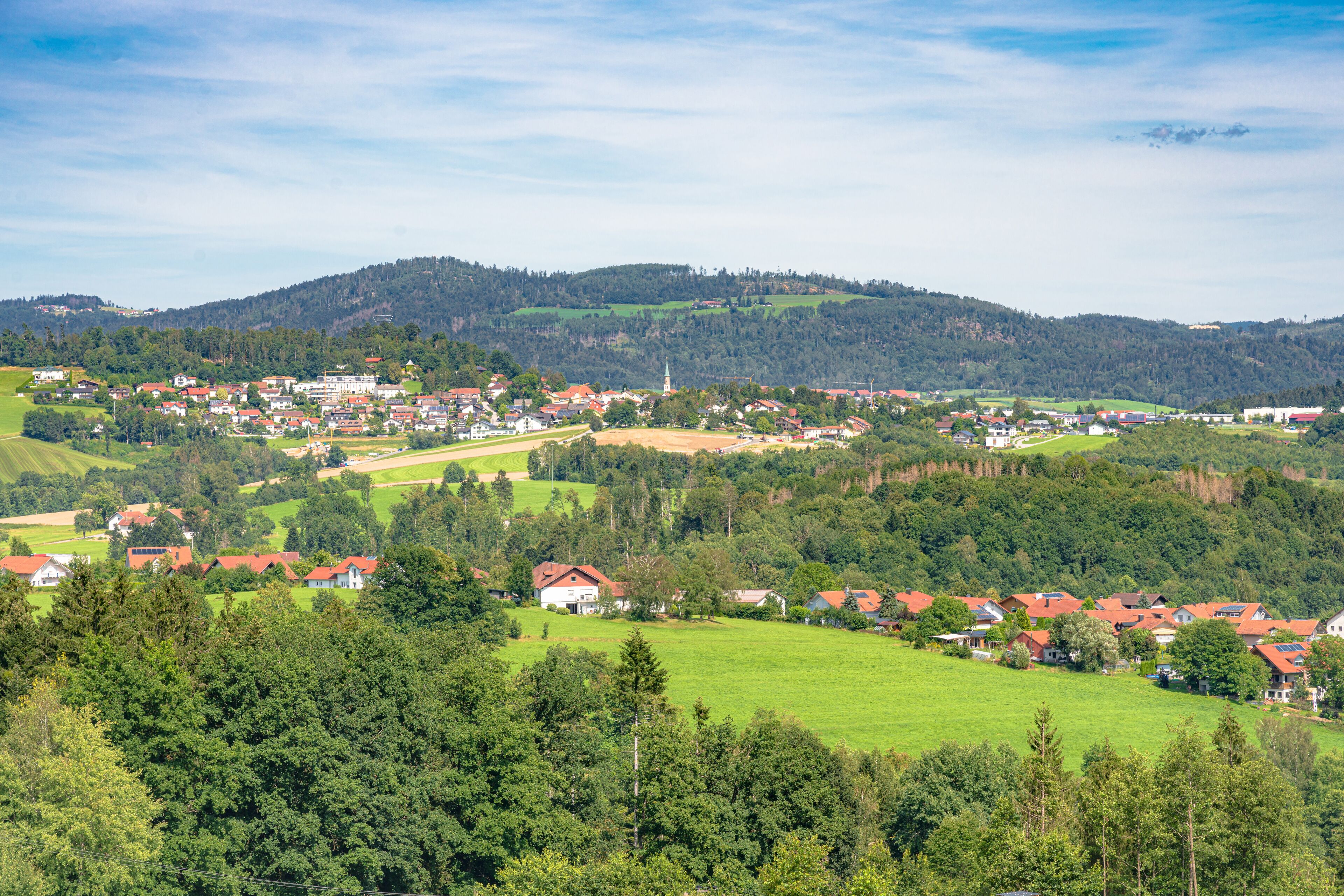 A rural town nestled in a valley with rolling hills and a prominent church spire.