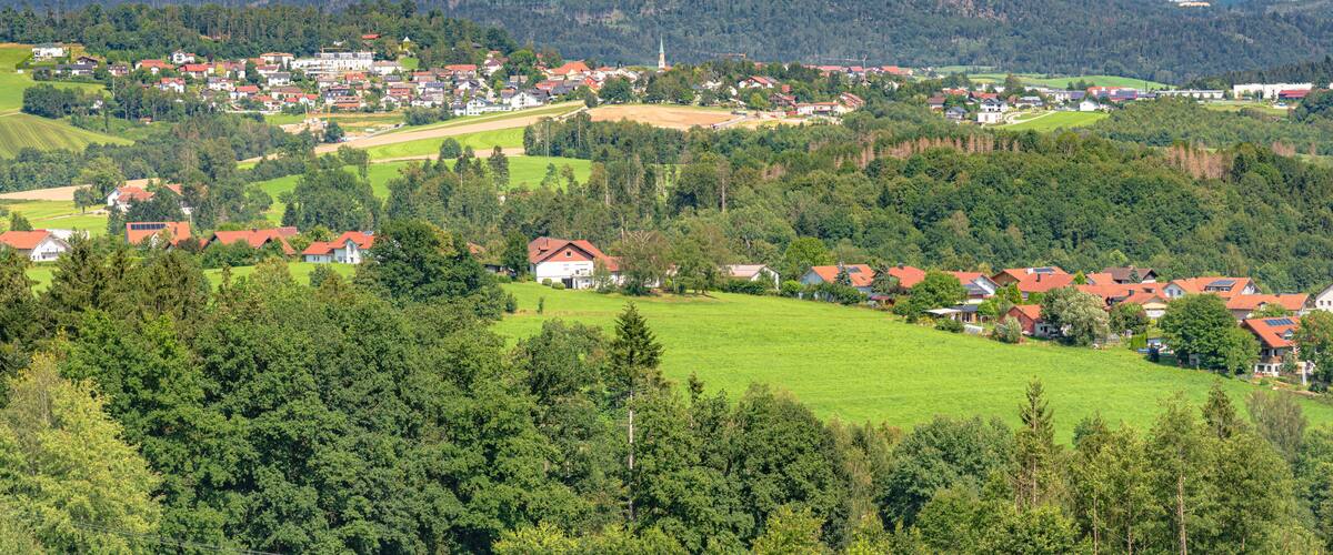 A rural town nestled in a valley with rolling hills and a prominent church spire.