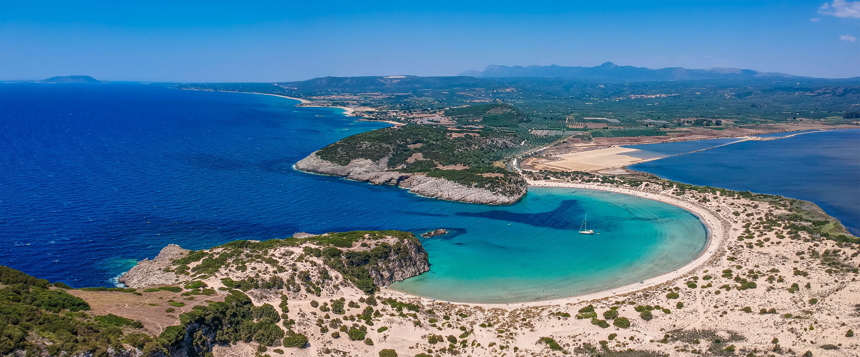Aerial panorama view of the famous semicircular sandy beach and lagoon of Voidokilia in Messenia, Greece