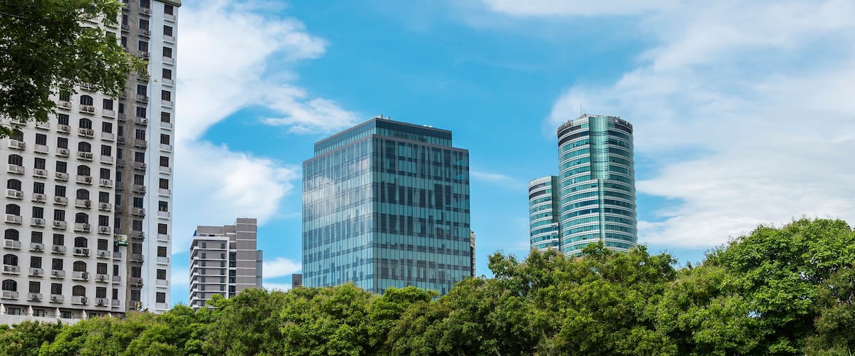 A cityscape with modern buildings and lush green trees.