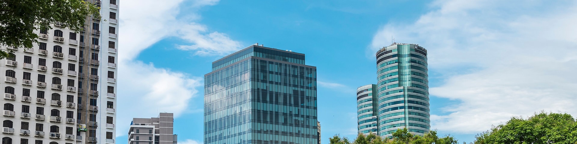 A cityscape with modern buildings and lush green trees.