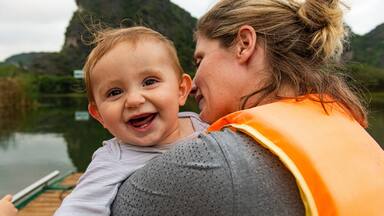 Vietnam, Mother with baby in boat at Trang An Scenic Landscape Complex