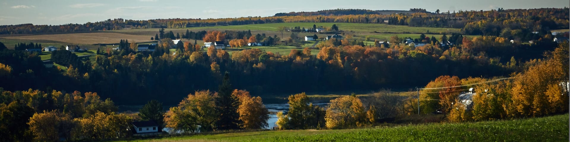A rural landscape with rolling hills, a river, and scattered houses.