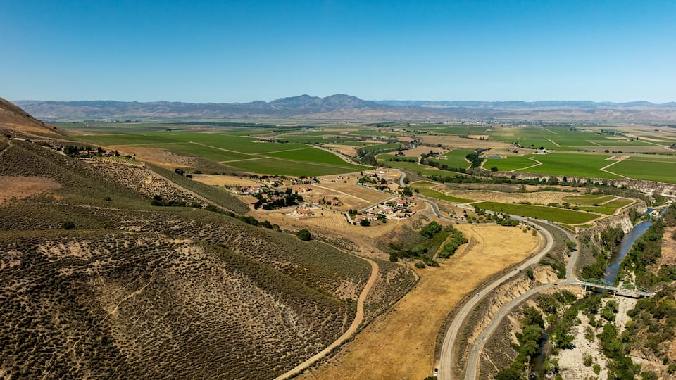 A valley with terraced fields, a winding river, and distant mountains.