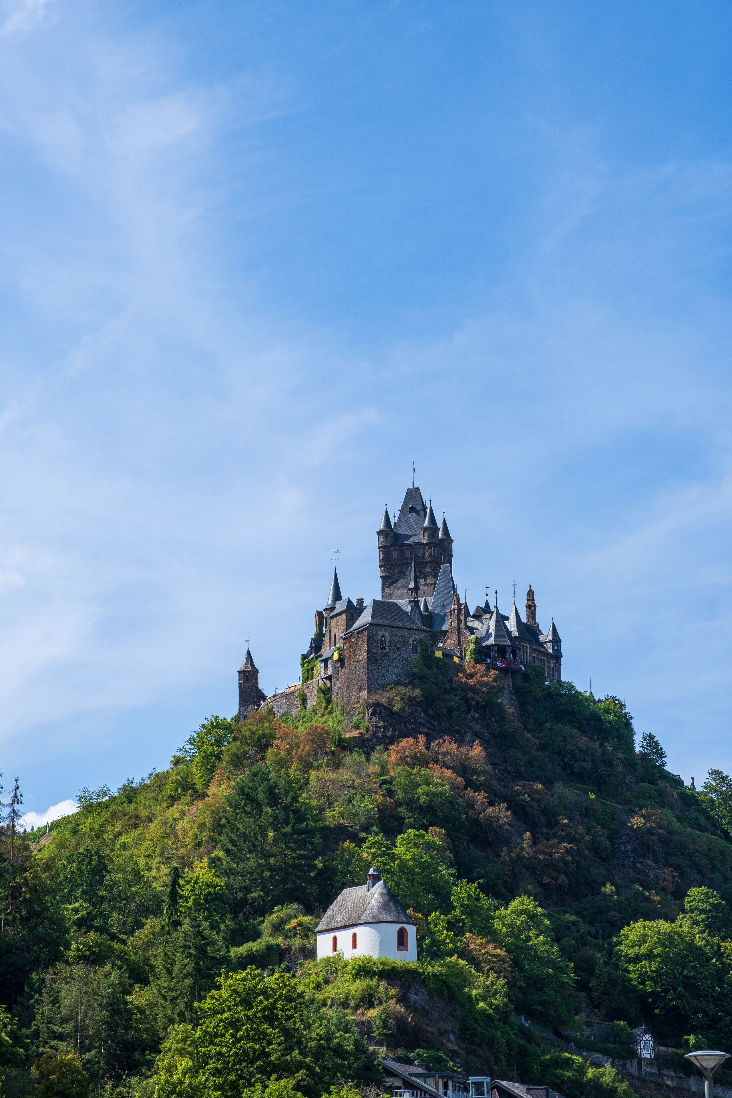 A castle on a hill with a small white building in the foreground.