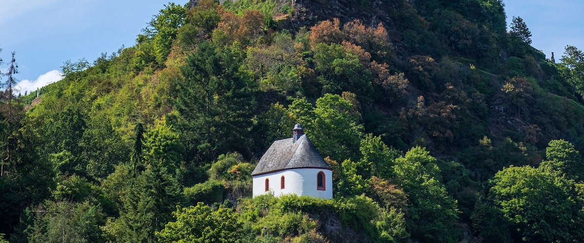 A castle on a hill with a small white building in the foreground.