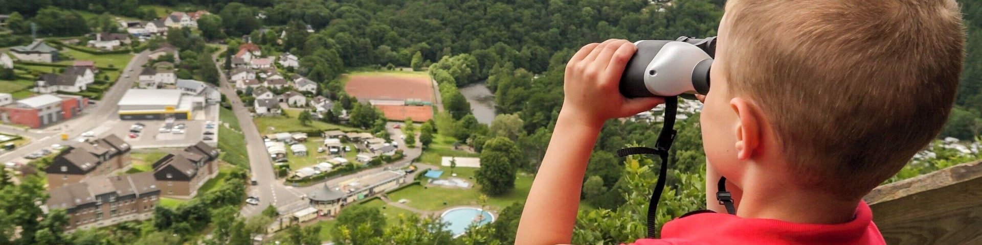 A child using binoculars to look at a town from a high vantage point.