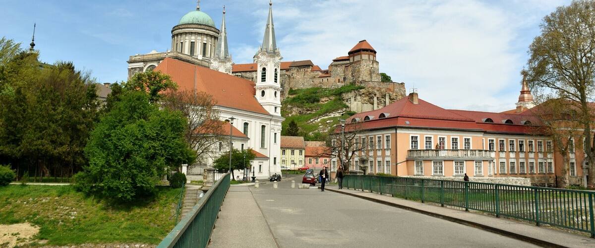 Une ville chargée d’histoire, avec une église remarquable, un château perché sur une colline et un pont verdoyant.