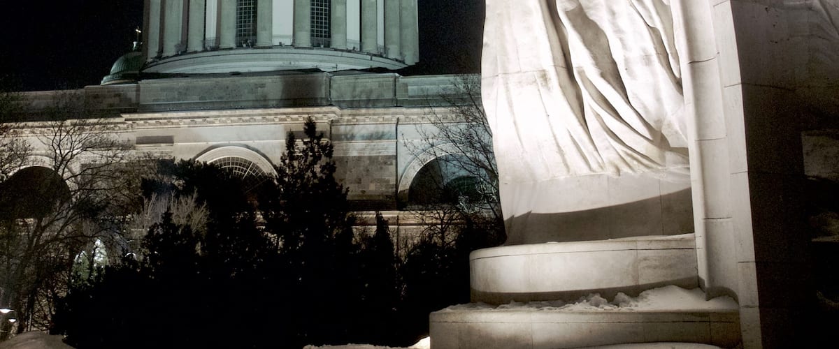 Szent István coronation statue with the dome of the Esztergom Basilica in the background. Photo taken at night in Esztergom, Hungary.