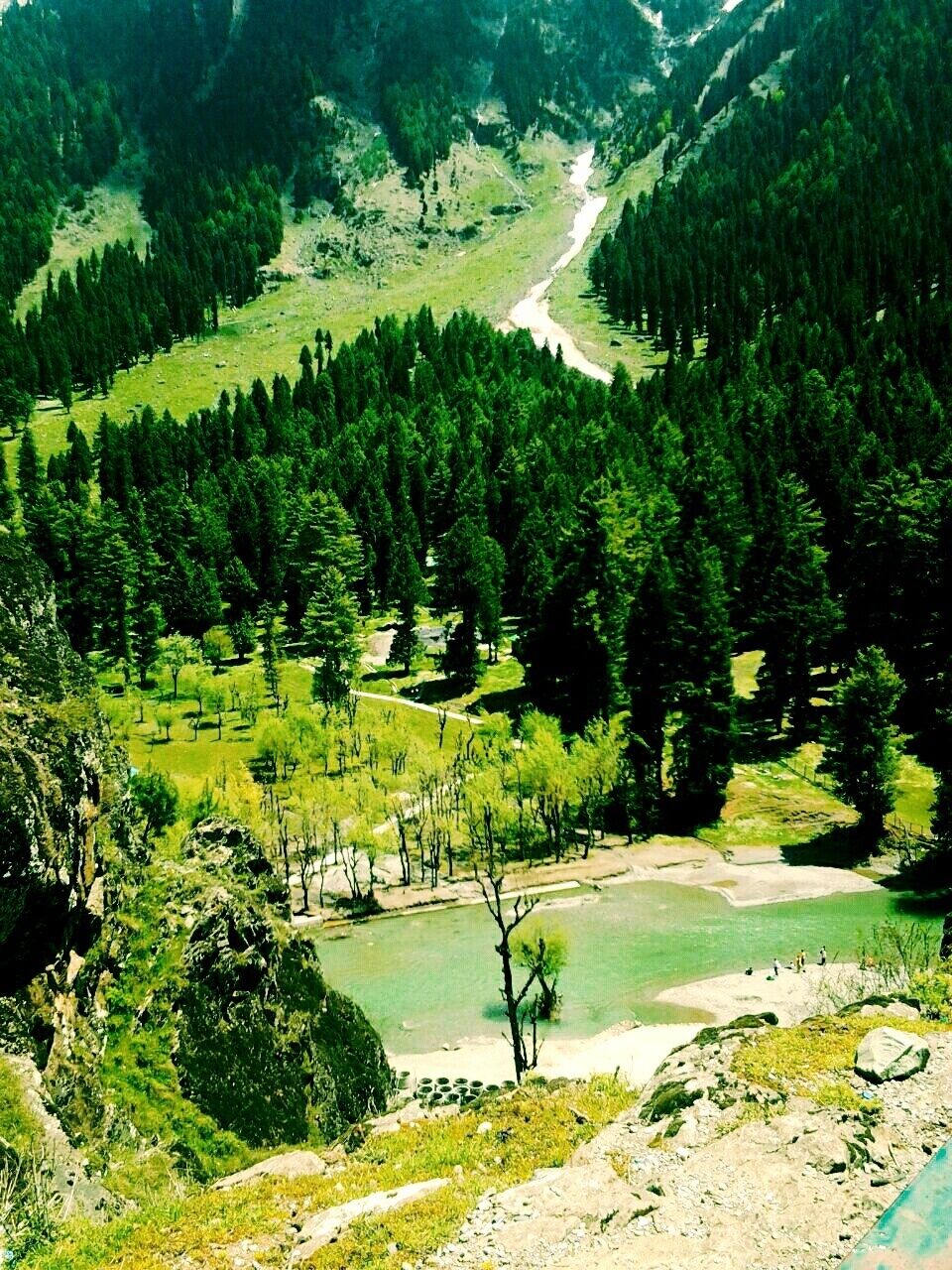 Un paisaje montañoso con un río, bosques densos y una masa de agua cristalina.