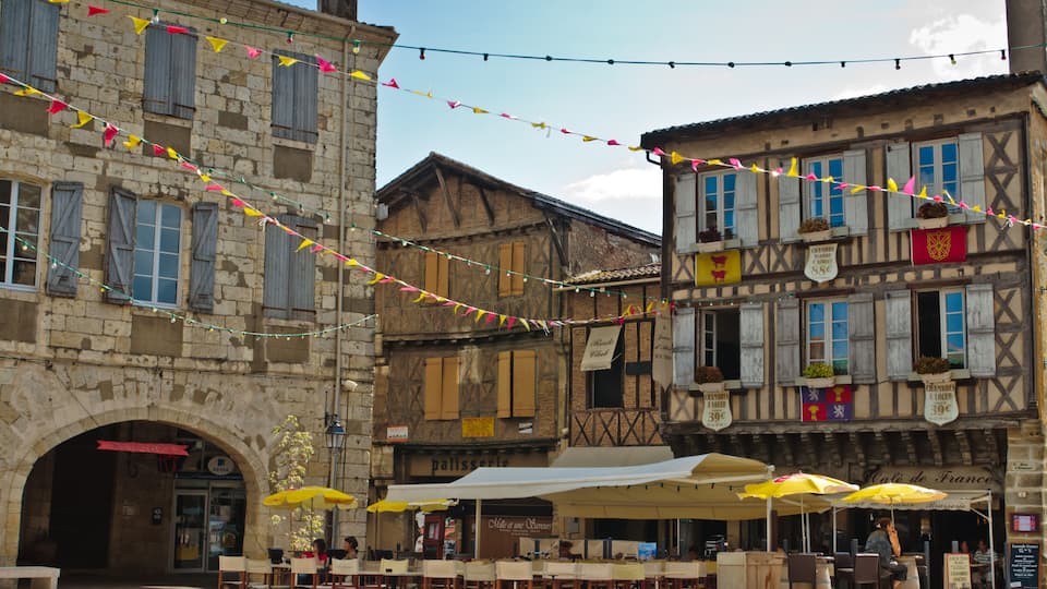 A historic European town square with outdoor seating and string lights.