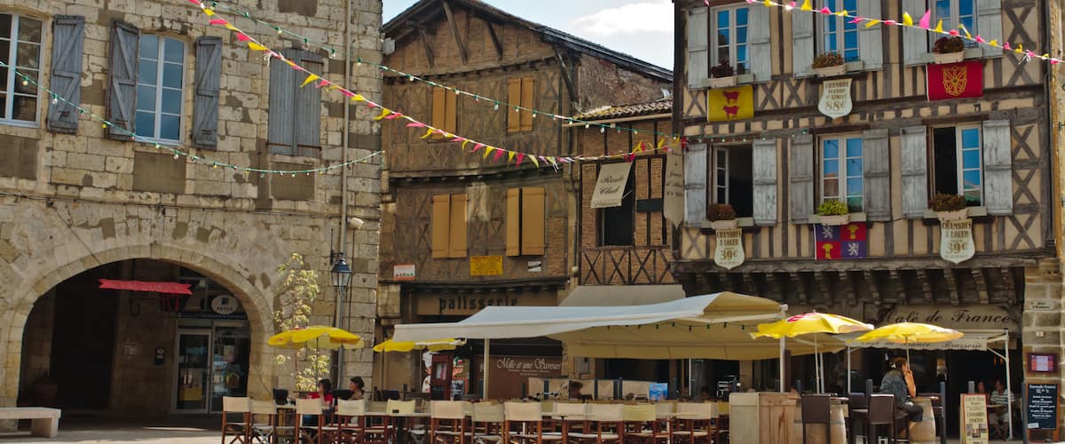 A historic European town square with outdoor seating and string lights.