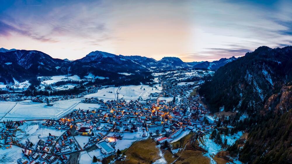 Germany, Bavaria,ÔøΩReitÔøΩimÔøΩWinkl, Helicopter view ofÔøΩsnow-coveredÔøΩmountain village at dawn