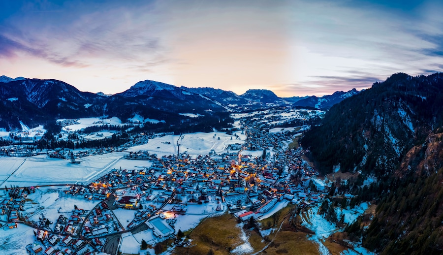 Germany, Bavaria,ÔøΩReitÔøΩimÔøΩWinkl, Helicopter view ofÔøΩsnow-coveredÔøΩmountain village at dawn