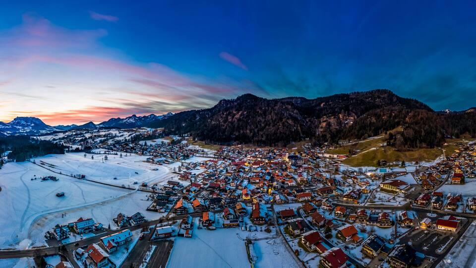 Germany, Bavaria, Reit im Winkl, Helicopter view of snow-covered mountain village at dawn