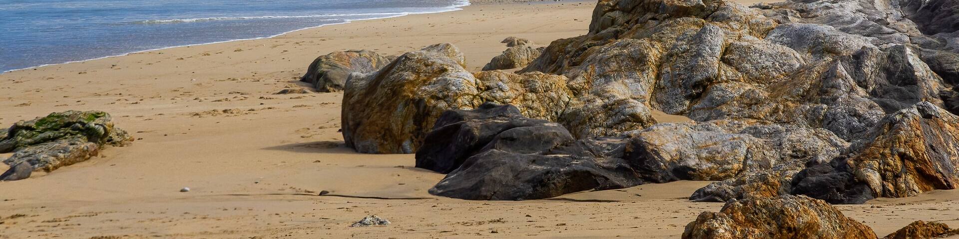 Sunny beach with surfers and rocks in the sand. Razo beach. Carballo, Galicia, Spain