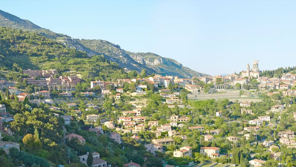 A town nestled in a valley with a prominent mountain in the background and a church with a bell tower.