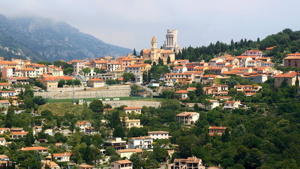 A town with red-roofed buildings, a prominent church, and a castle on a hill.