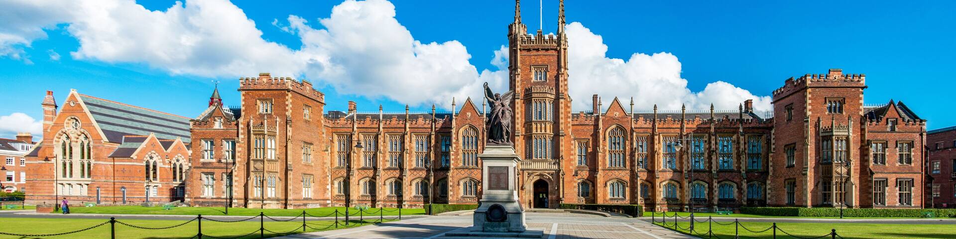 The Queen's University of Belfast with a grass lawn in sunset light. Wide panorama,