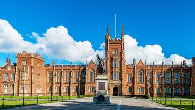 The Queen's University of Belfast with a grass lawn in sunset light. Wide panorama,