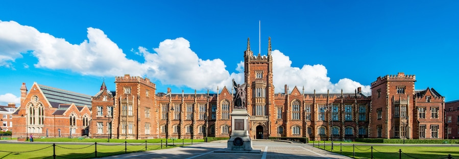 The Queen's University of Belfast with a grass lawn in sunset light. Wide panorama,