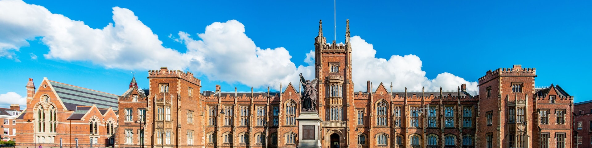 The Queen's University of Belfast with a grass lawn in sunset light. Wide panorama,