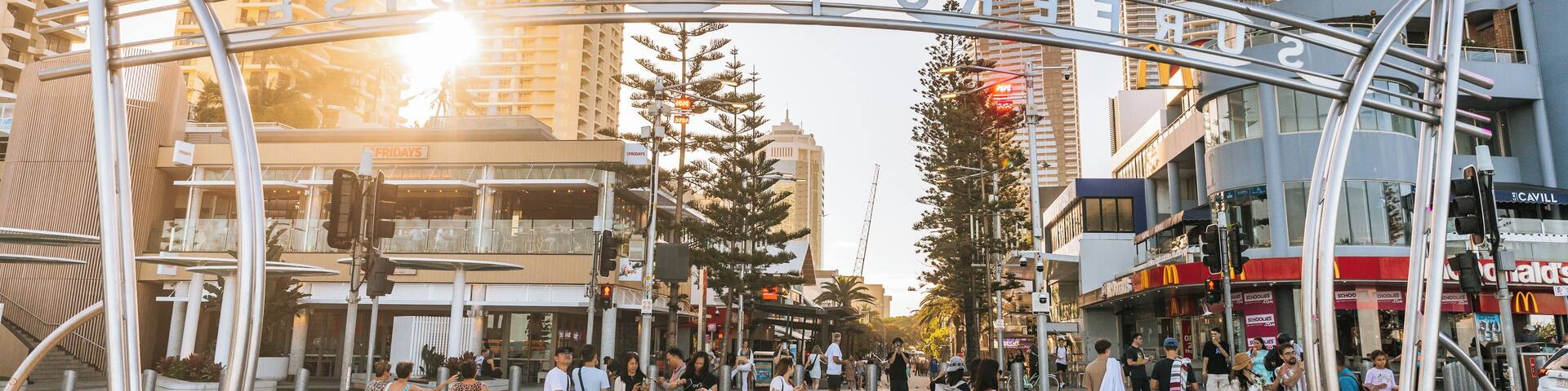 A busy urban street with modern buildings, a pedestrian crossing, and a clear sky.