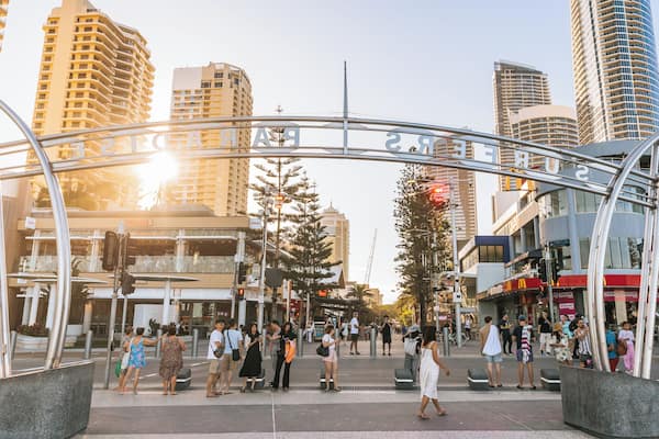 A busy urban street with modern buildings, a pedestrian crossing, and a clear sky.