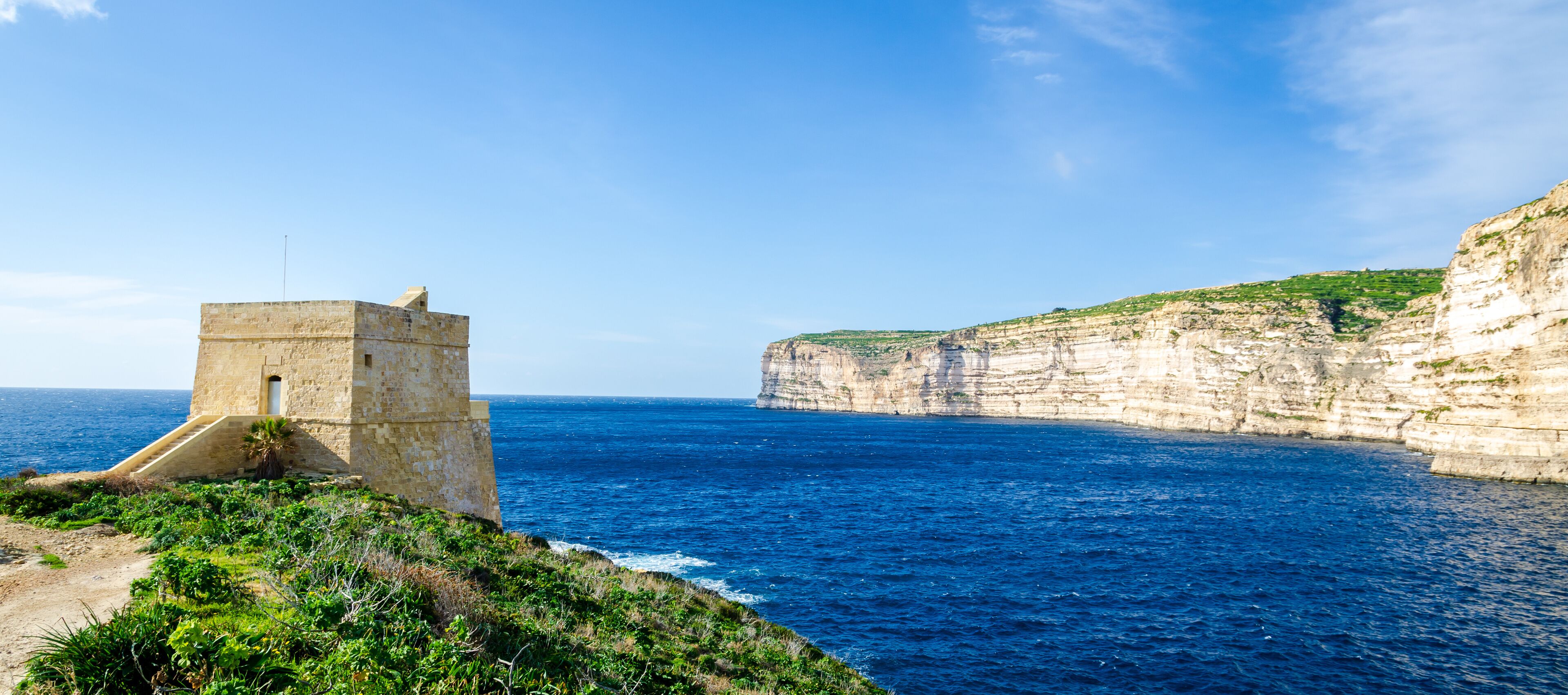 A coastal cliff with a stone tower overlooking the sea.