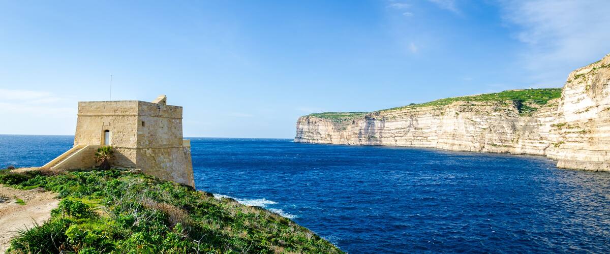 A coastal cliff with a stone tower overlooking the sea.