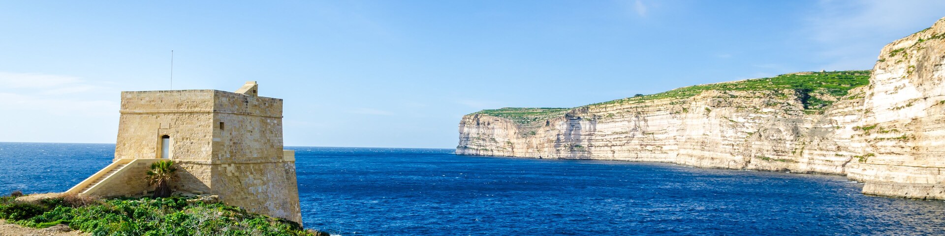 A coastal cliff with a stone tower overlooking the sea.