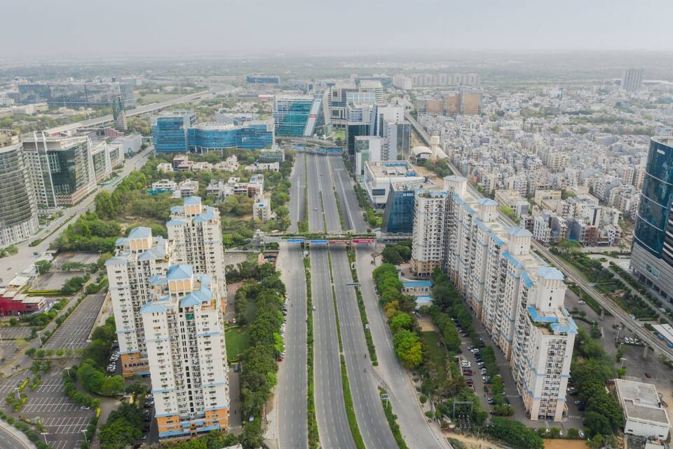 A cityscape with modern high-rise buildings, wide roads, and green spaces.