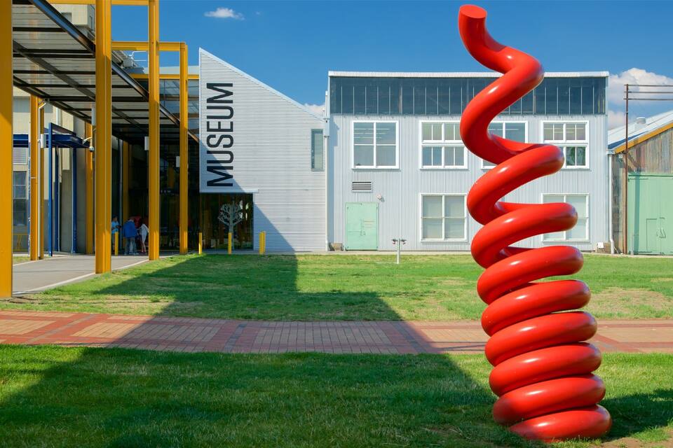 Un edificio moderno con un letrero que dice "Museum" y una gran escultura en espiral roja al frente.