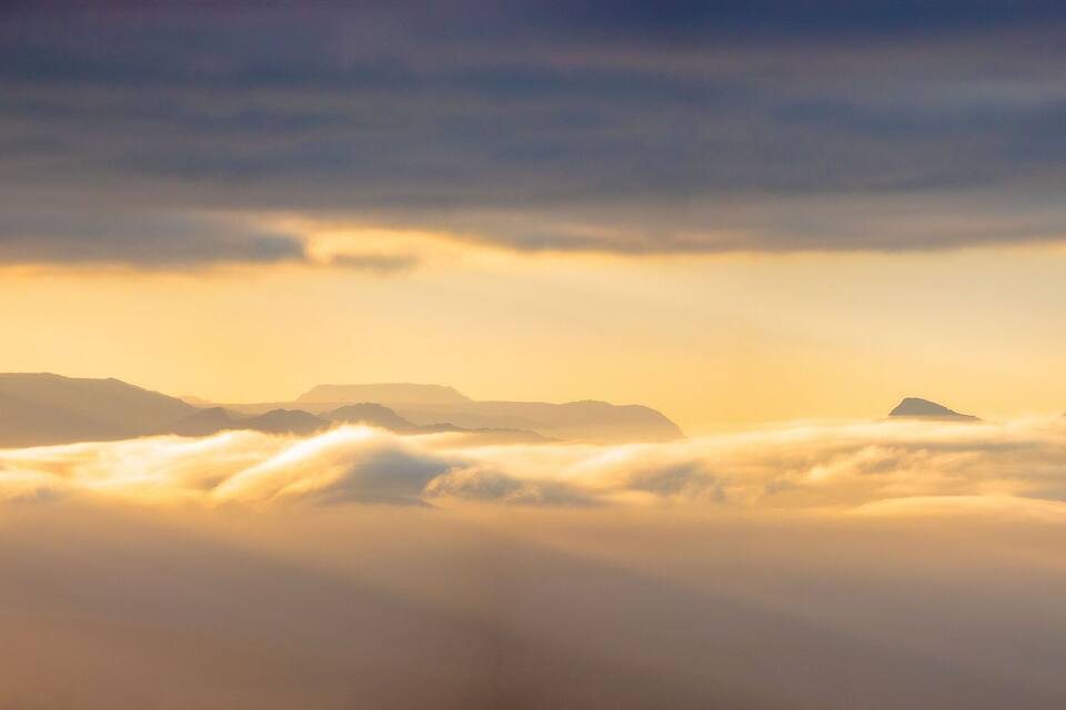 Een bergketen met wolken bij zonsopkomst of zonsondergang.