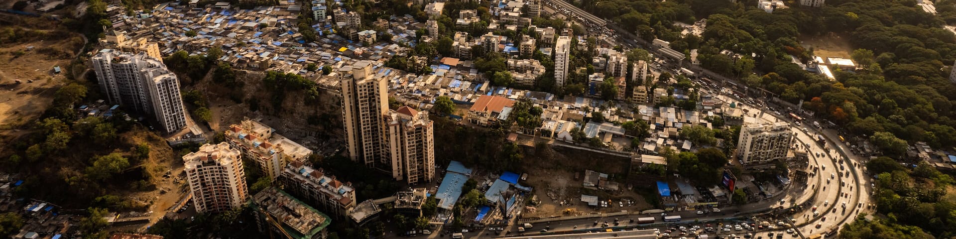 Aerial view of dense urban sprawl juxtaposed against lush greenery and a tranquil Powai lake under the golden light of the setting sun, Powai,Mumbai, Maharashtra, India.
