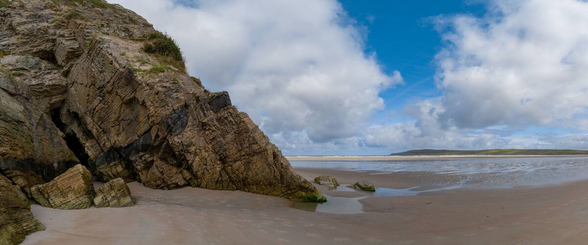 A rocky coastline with a sandy beach and a clear sky.