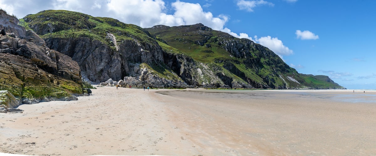 Een strand met een rotsachtige klif en een heldere lucht.