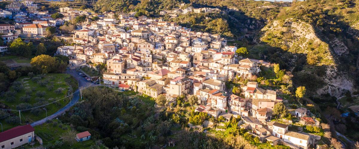 A densely packed hillside town with buildings nestled among trees and hills.
