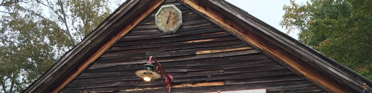 Ein rustikales Gebäude mit der Aufschrift „OLD SAUTEE STORE“, amerikanischen Flaggen, hängenden Pflanzen und Kürbissen.