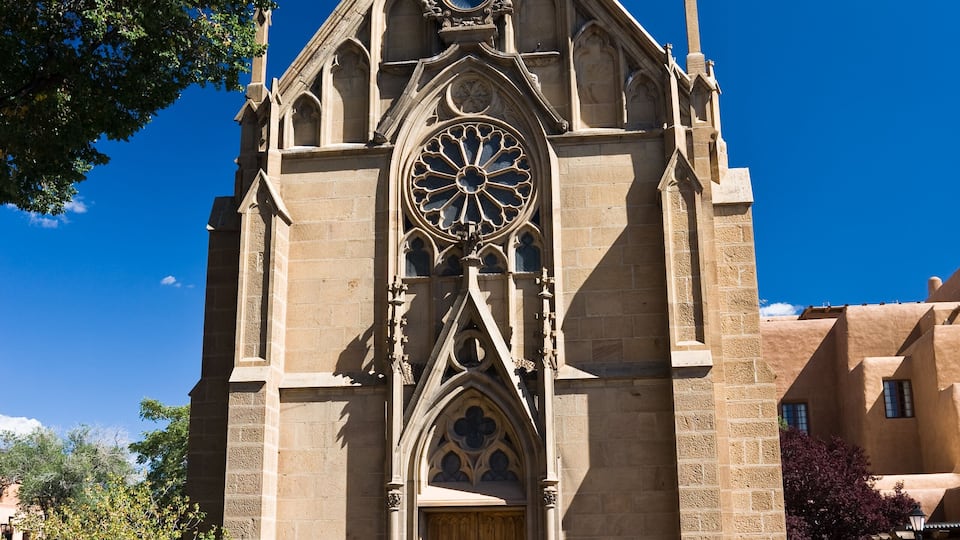 A Gothic-style church with a large rose window and a statue on top.