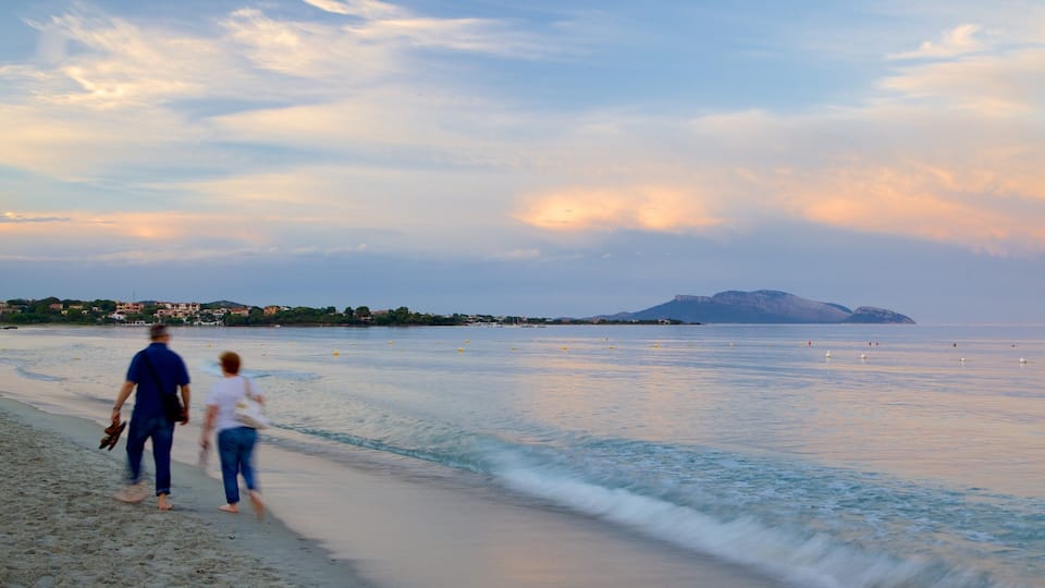 A beach with people walking, a calm sea, and distant mountains.